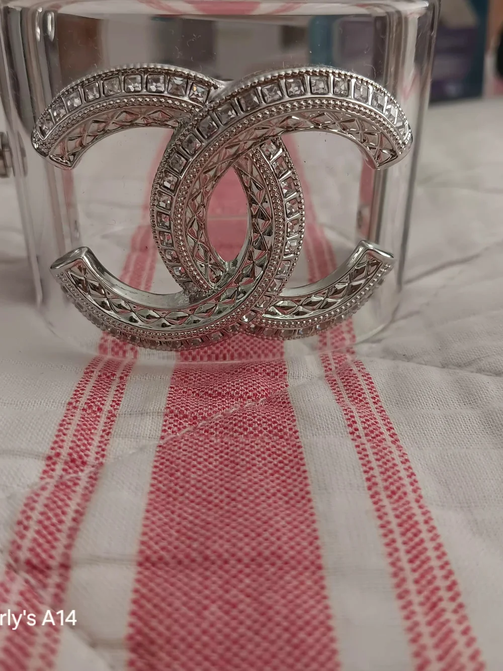Chanel silver CC logo embedded with crystal baguette stones on a transpar
